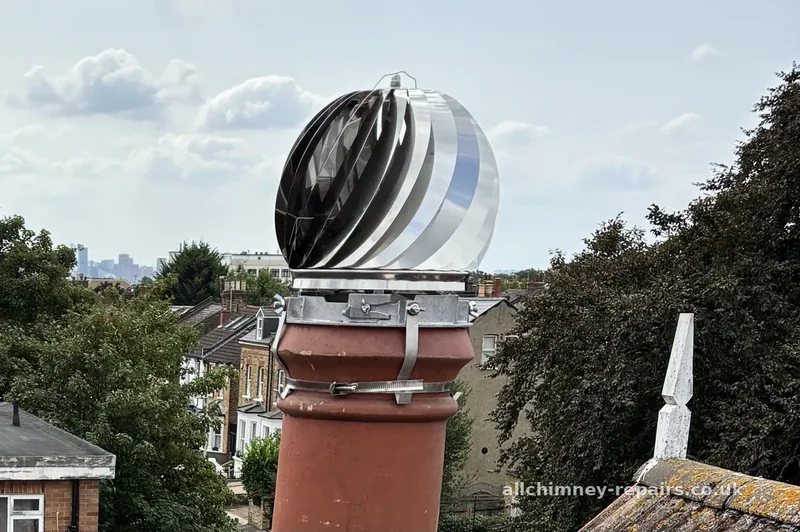 Chimney repair specialist — spinning anti-downdraught cowl strap fixed to existing chimney pot, creates upward draw when rotating, eliminates smoke spillage, Romford | Allchimney Repairs